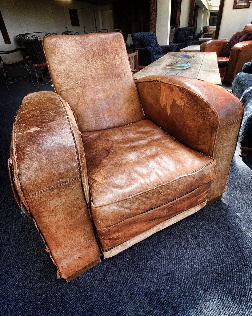 A well loved leather club chair on a deep blue carpet