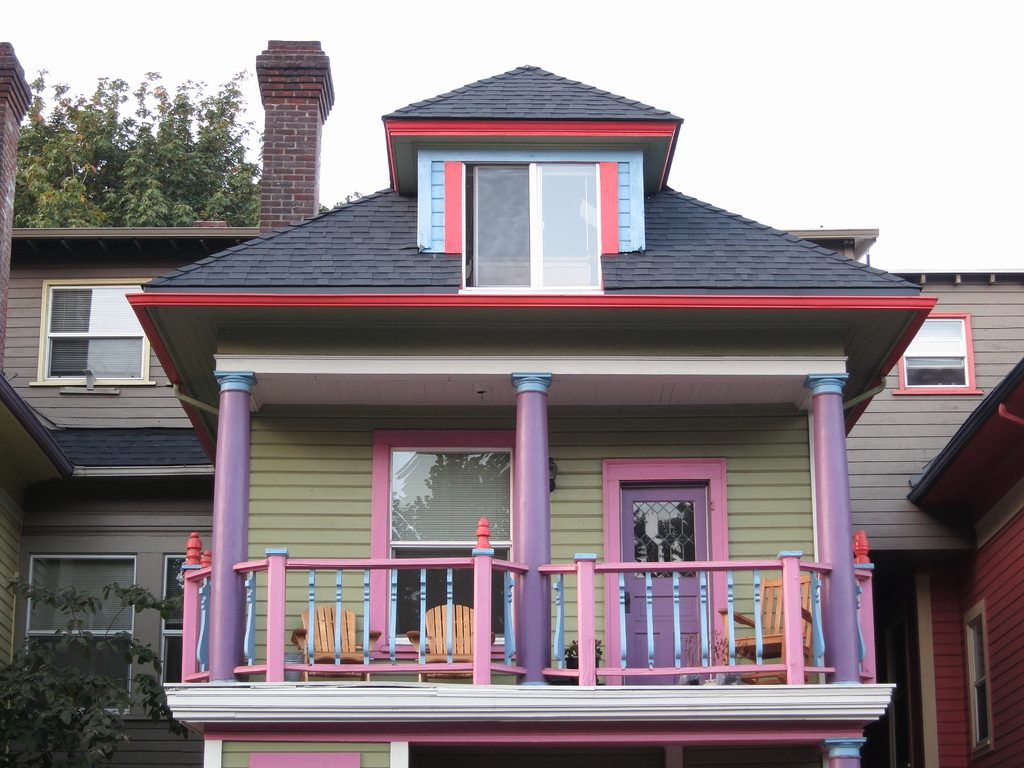 A colourful two storey house with a pink and lilac front porch